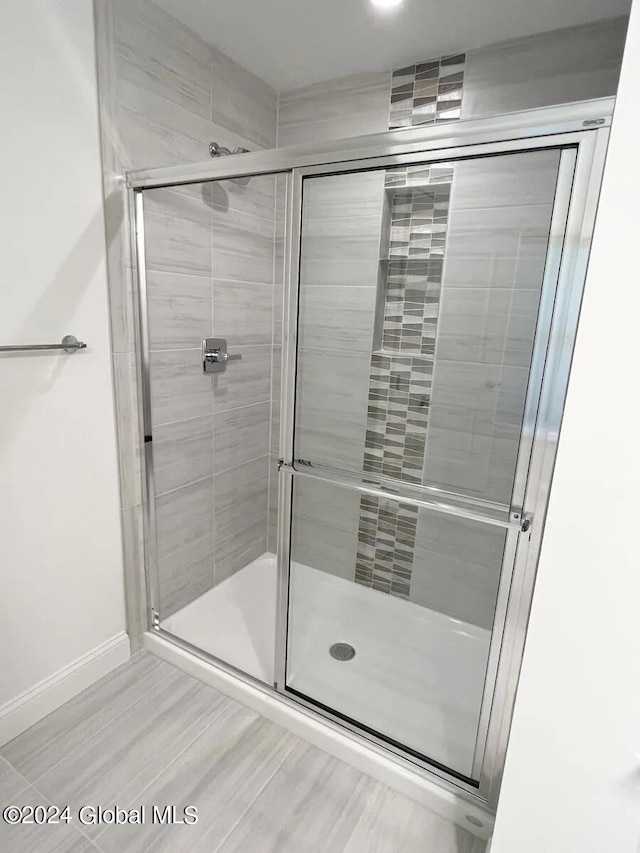 bathroom with a shower with shower door and hardwood / wood-style flooring