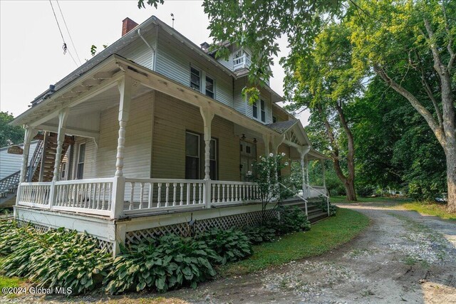 view of side of home featuring covered porch