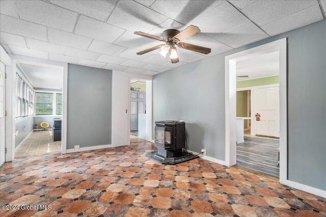 unfurnished living room with a wood stove and ceiling fan