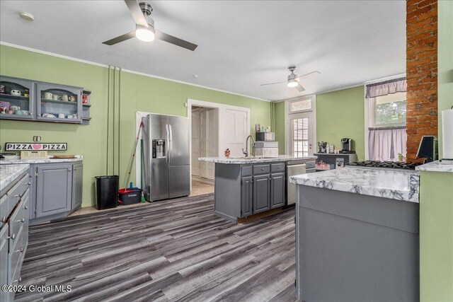 kitchen featuring gray cabinetry, dark hardwood / wood-style floors, a center island with sink, appliances with stainless steel finishes, and ornamental molding