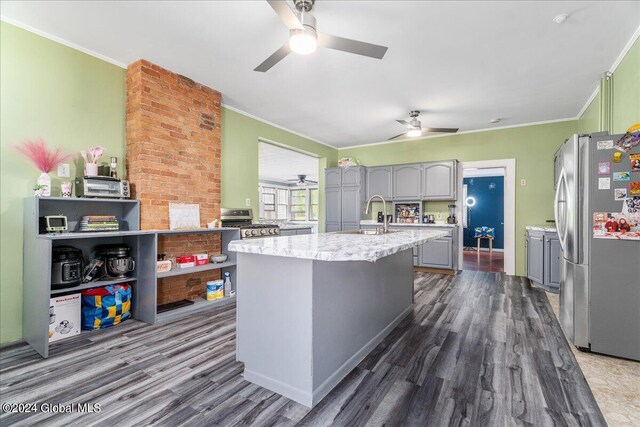 kitchen with an island with sink, stainless steel appliances, dark hardwood / wood-style floors, and ornamental molding