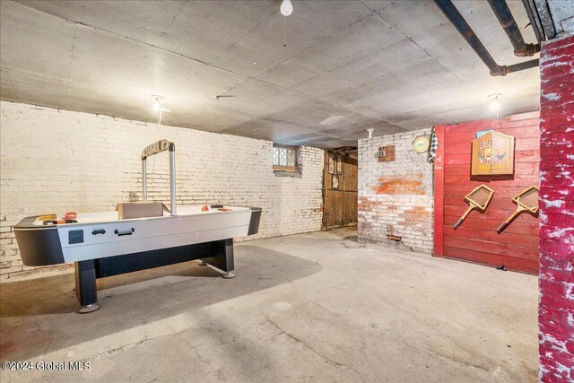 rec room featuring concrete floors and brick wall