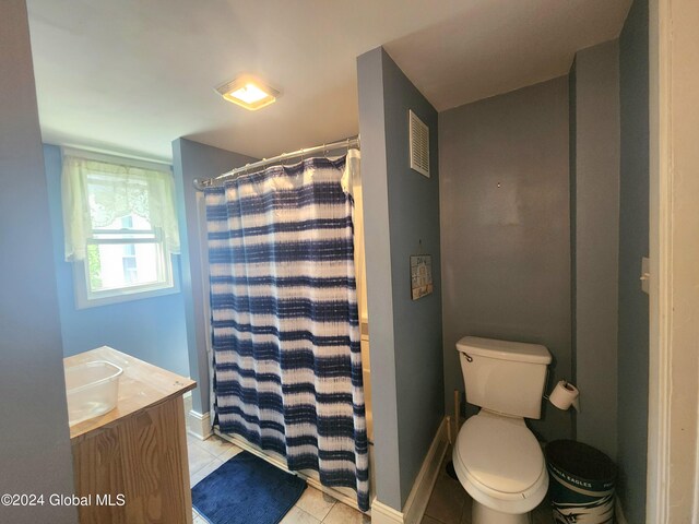 bathroom with tile patterned flooring, vanity, toilet, and walk in shower