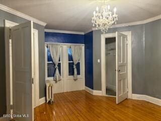 interior space with radiator, crown molding, hardwood / wood-style floors, and an inviting chandelier