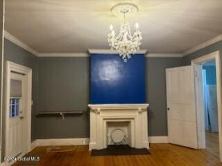 unfurnished living room featuring hardwood / wood-style floors, crown molding, and a notable chandelier