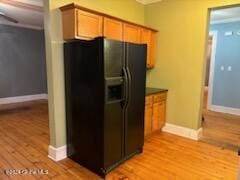 kitchen with black fridge with ice dispenser, light hardwood / wood-style flooring, and ceiling fan