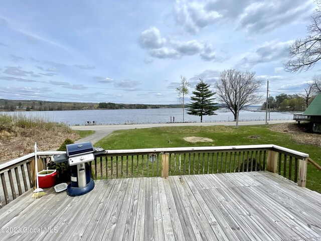 wooden terrace featuring a grill, a yard, and a water view