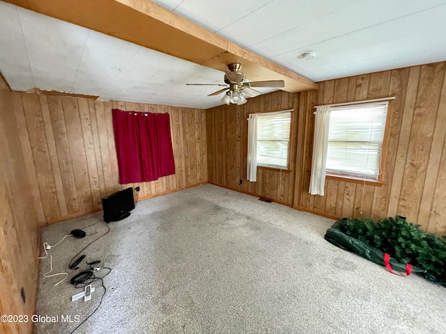 spare room with light carpet, ceiling fan, and wooden walls