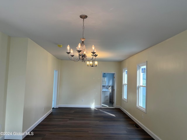 unfurnished room featuring an inviting chandelier and dark wood-type flooring