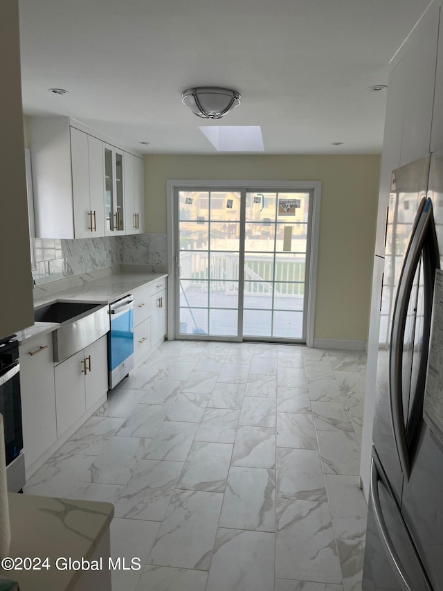 kitchen with stainless steel appliances, white cabinetry, tasteful backsplash, and sink