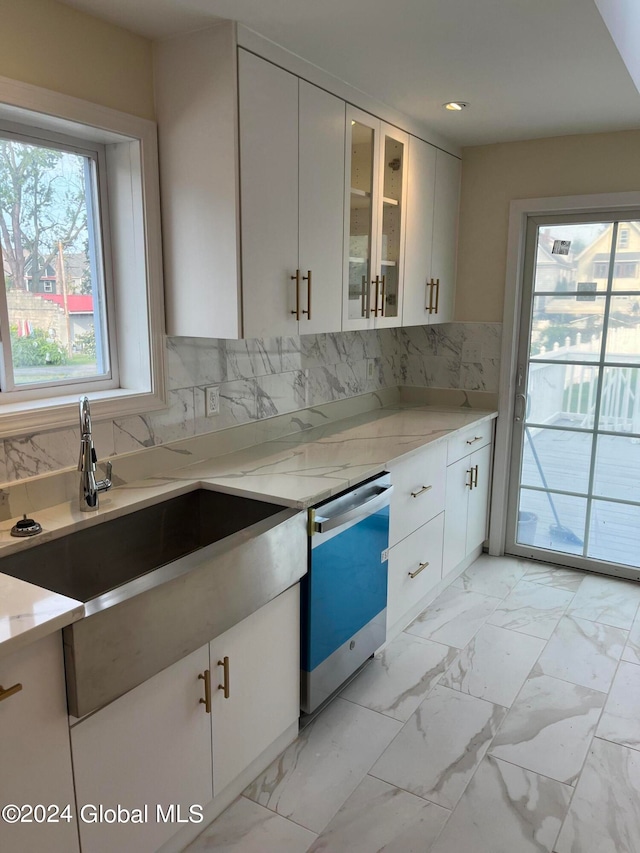 kitchen featuring white cabinets, light stone countertops, and backsplash