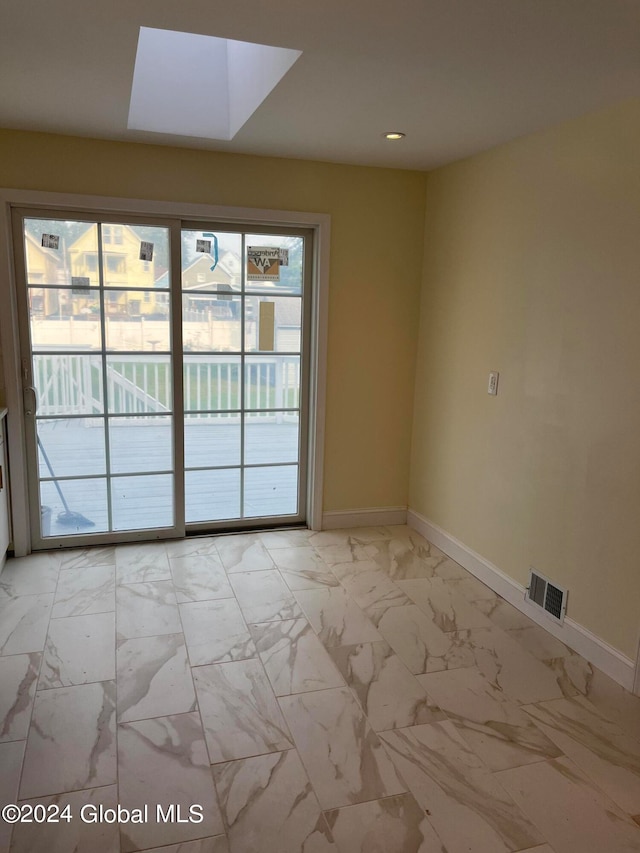 empty room featuring a skylight and plenty of natural light