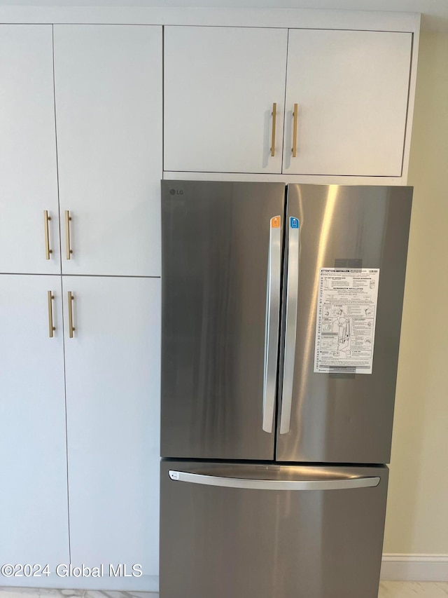 room details with white cabinets and stainless steel refrigerator