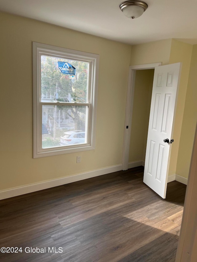 empty room with dark hardwood / wood-style floors and a healthy amount of sunlight