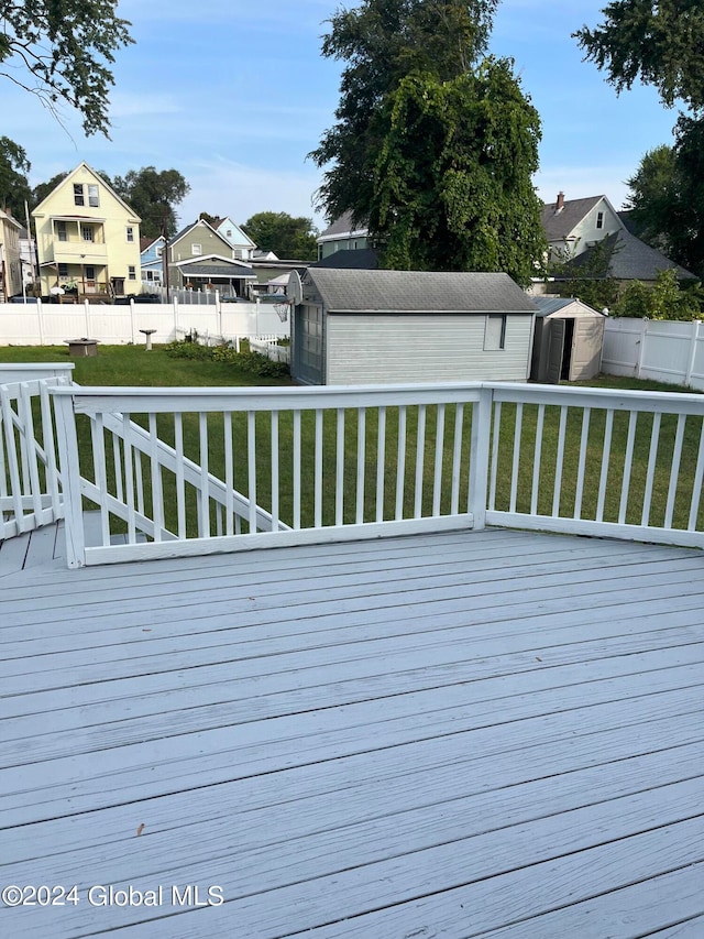 wooden deck featuring a yard and a storage unit