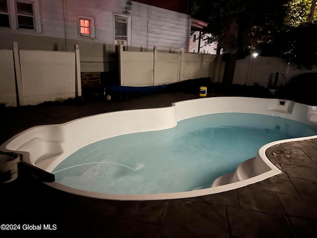 pool at twilight featuring a jacuzzi