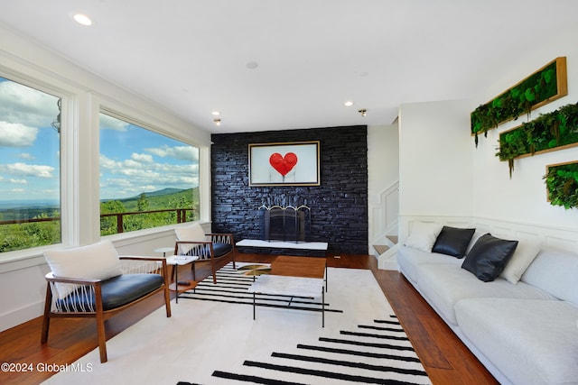 living room featuring a stone fireplace and wood-type flooring