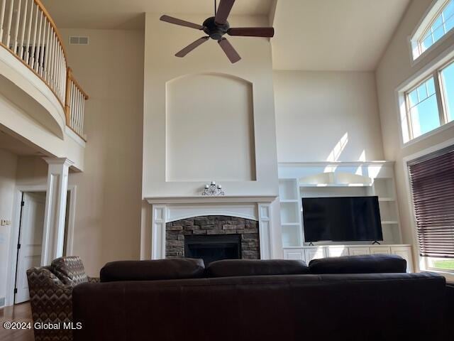 living room featuring a high ceiling, ceiling fan, and a fireplace