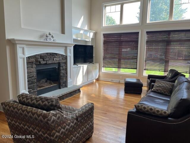 living room with a high ceiling, light wood-type flooring, and a fireplace