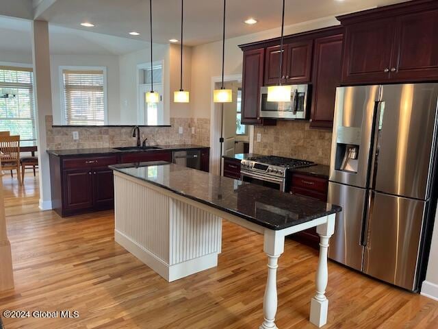 kitchen with a center island, stainless steel appliances, a kitchen breakfast bar, and light hardwood / wood-style floors