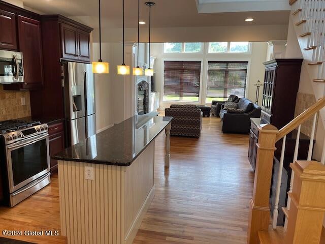 kitchen featuring light hardwood / wood-style flooring, stainless steel appliances, hanging light fixtures, and decorative backsplash