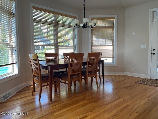 dining room with light hardwood / wood-style flooring and an inviting chandelier