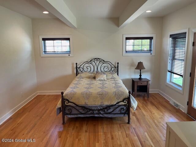 bedroom with beamed ceiling and light hardwood / wood-style flooring