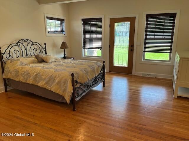 bedroom with hardwood / wood-style floors and access to outside