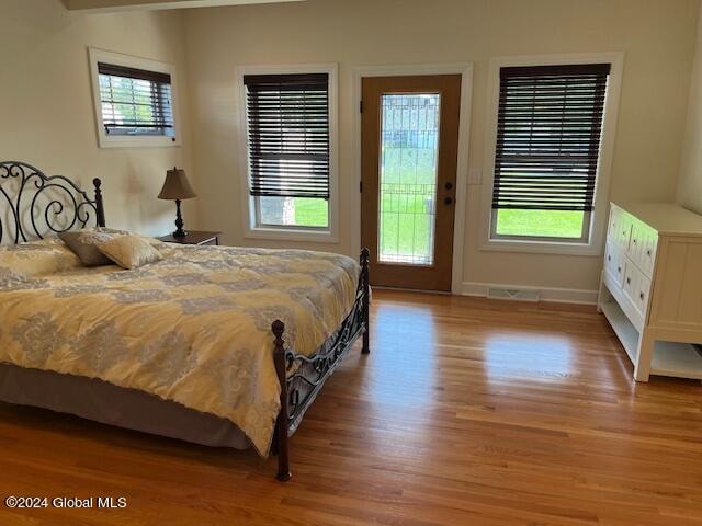 bedroom with multiple windows, light hardwood / wood-style floors, and access to outside