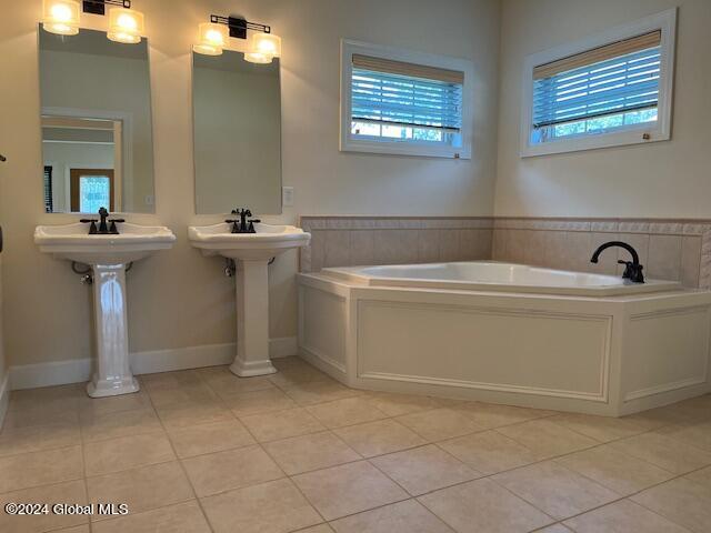 bathroom with plenty of natural light, a bathing tub, double sink, and tile patterned floors