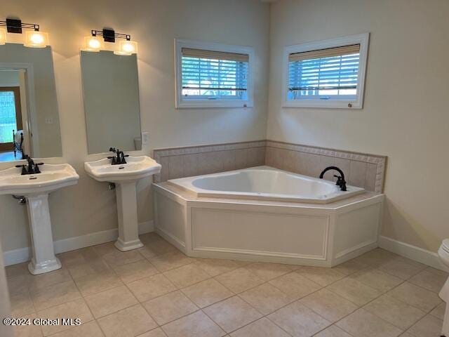 bathroom featuring a wealth of natural light, double sink, a tub, and tile patterned flooring