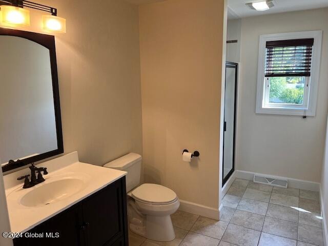 bathroom with a shower with shower door, tile patterned flooring, toilet, and vanity