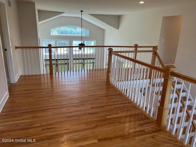 hall with lofted ceiling and wood-type flooring