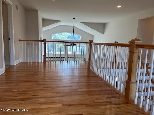 corridor featuring lofted ceiling, an inviting chandelier, and wood-type flooring