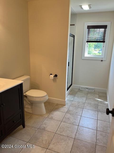 bathroom with tile patterned floors, toilet, a shower with door, and vanity