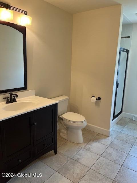 bathroom with a shower with door, vanity, toilet, and tile patterned flooring