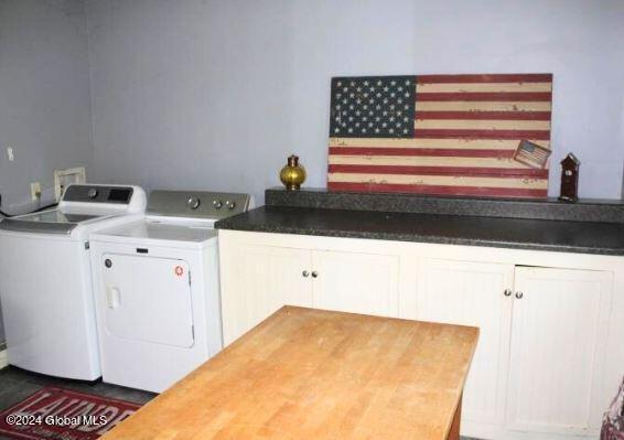 clothes washing area featuring independent washer and dryer and cabinets