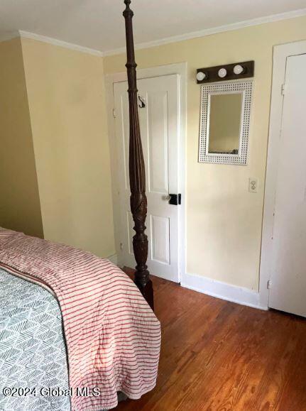 bedroom with crown molding and dark hardwood / wood-style floors