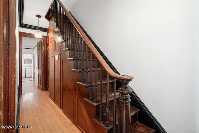 stairway featuring independent washer and dryer, hardwood / wood-style flooring, and crown molding