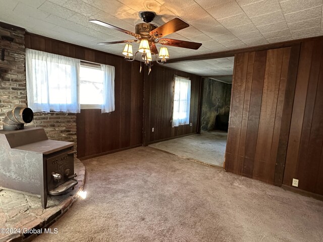 interior space with wood walls, ceiling fan, and light colored carpet