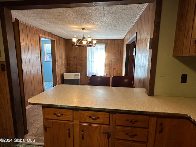 kitchen with an inviting chandelier, wooden walls, carpet, and hanging light fixtures