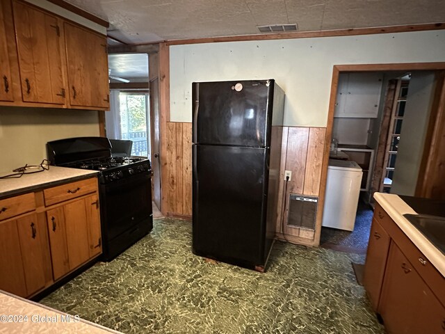 kitchen with a textured ceiling, wooden walls, and black appliances