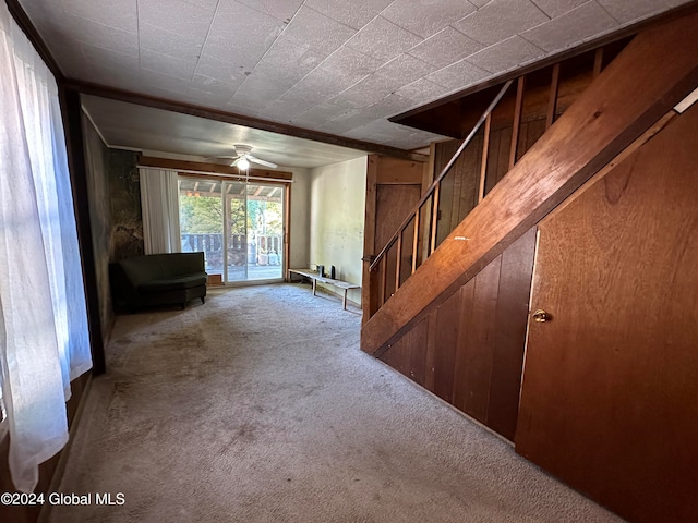 interior space with wooden walls, ceiling fan, and light colored carpet