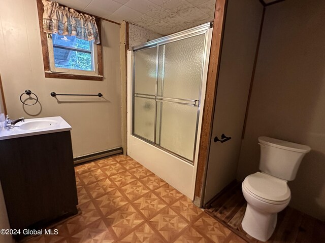 full bathroom featuring vanity, parquet flooring, a baseboard radiator, bath / shower combo with glass door, and toilet