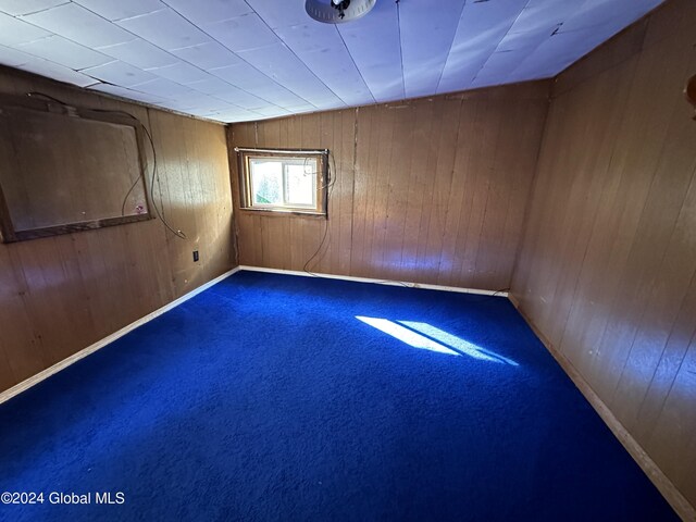 carpeted spare room with wood walls