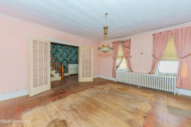 spare room with radiator, crown molding, french doors, and hardwood / wood-style flooring