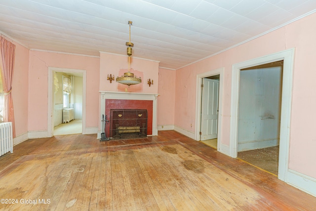 unfurnished living room with radiator, wood-type flooring, and crown molding