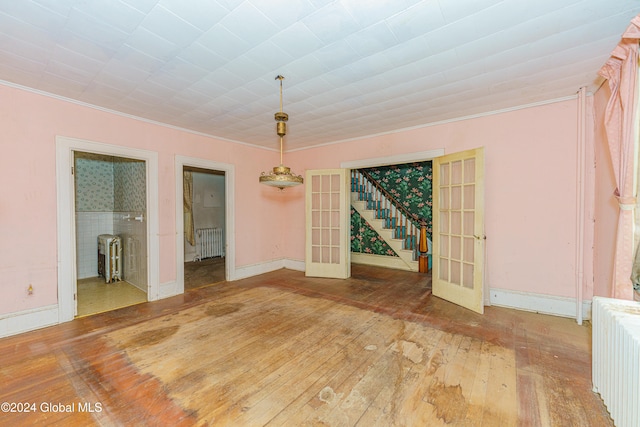 unfurnished room with wood-type flooring, radiator heating unit, and french doors