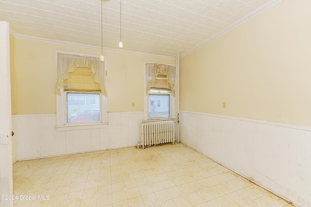 unfurnished room featuring wood walls, a healthy amount of sunlight, radiator heating unit, and crown molding