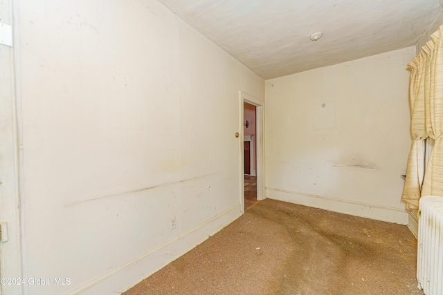 carpeted spare room featuring radiator heating unit